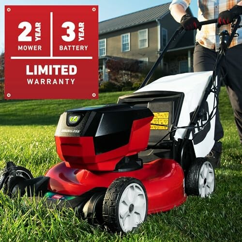 Person using a red and black lawn mower with a limited warranty sign.