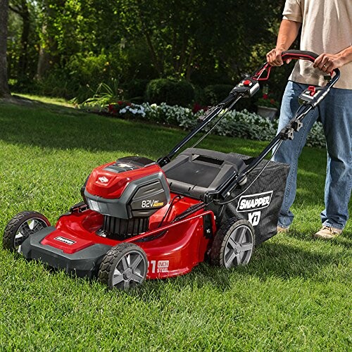 Person using a red lawn mower on grass